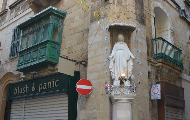 statue of a woman saint (Mary?) built into the corner of a limestone building in Malta
