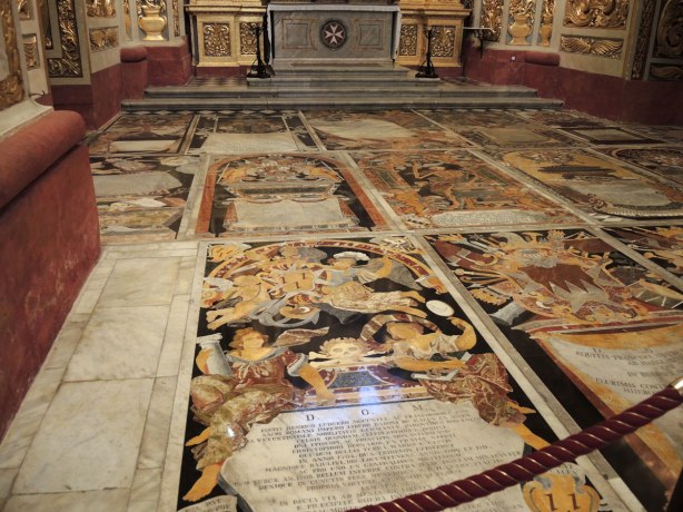 black, white, orange, gold tiles form memorials in the floor of St. Johns Co Cathedral in Valletta Malta. There are numberous angels, skulls and skeleton motifs that cover almost every inch of the cathedral floor.