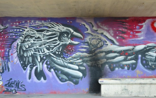 A large bird in grey tones flying on a purple background, graffiti on a wall.
