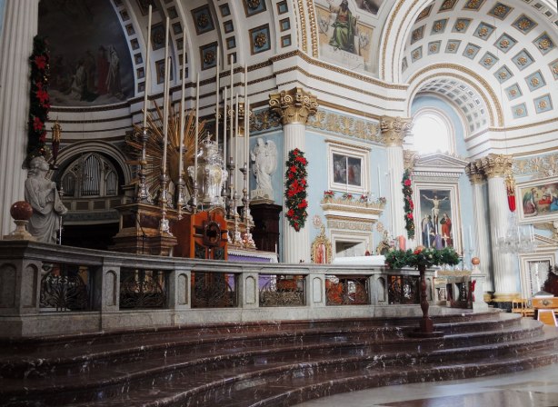 inside of a church decorated in light blue, white and gold in Mosta Malta. The main altar is on the left
