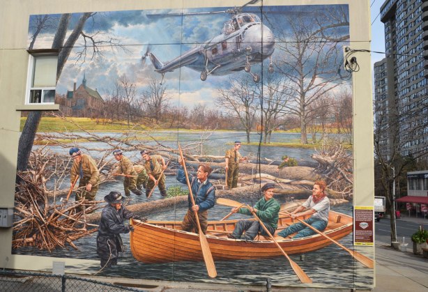 large painting of men in boats, helicopter overhead