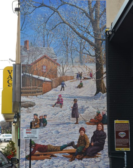 large vertical mural depicting a hill in winter.   Bare trees, kids on tobaggons.  