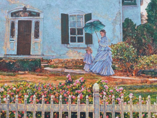 A woman and a girl in long light blue dresses are walking in front of a house.  The woman is carrying a blue parasol.  There is a white picket fence and flowering shrubs in the foreground of the picture. 