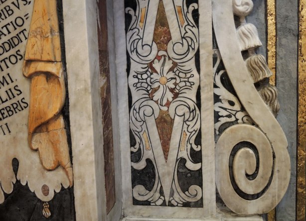 Detail of stone work on a wall. Swirls, flower, words