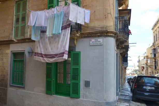 Laundry hanging from a balcony in Valletta Malta, limestone buildings and painted shutters.