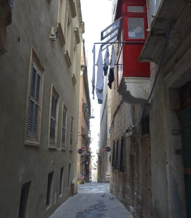 Laundry hanging from a balcony in Valletta Malta, limestone buildings and painted shutters.