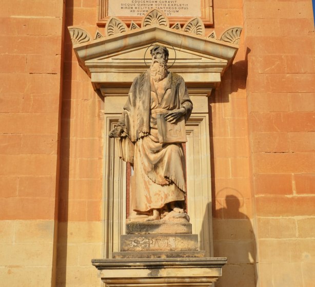 statue of a man holding a book, St. Paul (or St. Paulus) according to the inscription under the statue. Limestone, on the front of a church in Mosta Malta