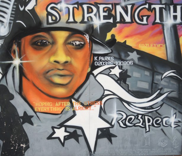 Part of a mural showing a black man's face. The words strength and respect are written there. Also 4 white stars, and the words "hoping after the stress everything is okay."