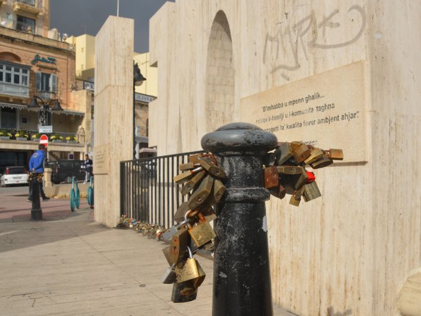 many padlocks are locked to a short post next to a LOVE sculpture