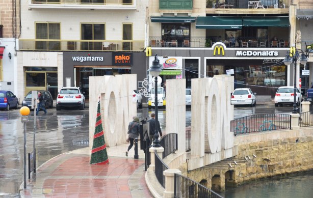 people walking through the LOVE sculpture as it is in two halves, one on either side of the sidewalk.
