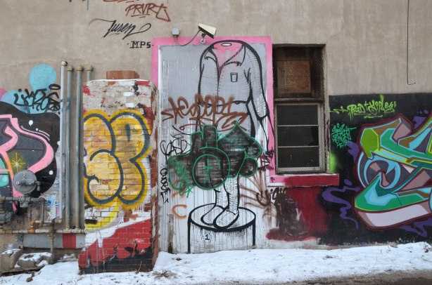 jumble of different scribbles and tags and old graffiti along a wall. 