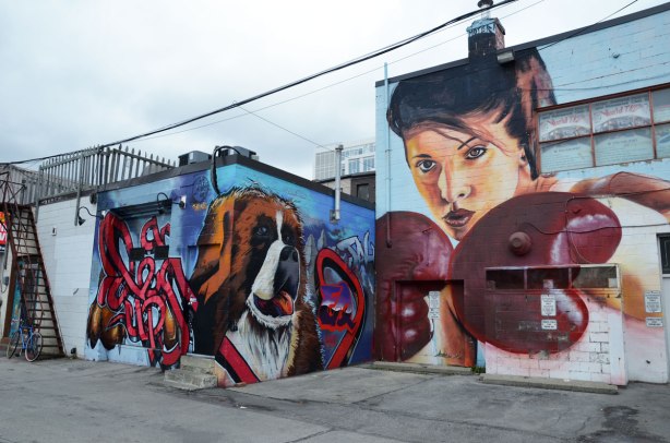 large mural of a woman with boxing gloves on. Beside her is a picture of a large dog's face.