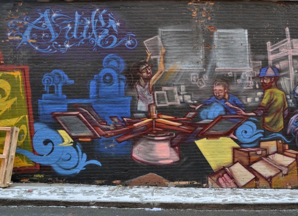 mural scene of two men working on a machine that is printing designs on t-shirts