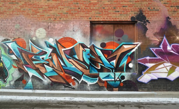 colorful graffiti tags on a brick wall