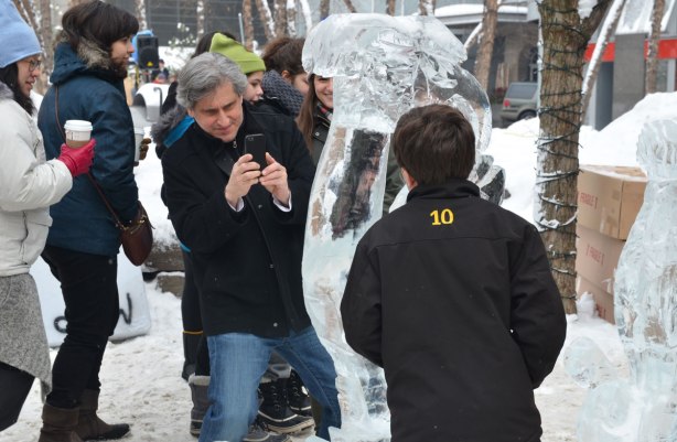 A father is taking a photograph of his son beside an ice sculpture