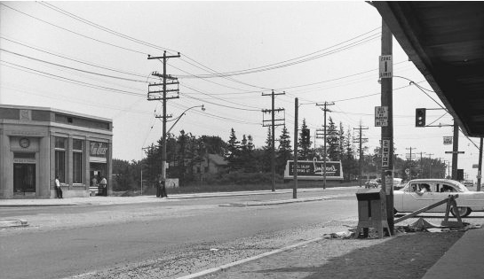 An old black and white photo from 1955 showing the intersection of Yonge and Sheppard.  Not much development, an old car is waiting at a street light. 