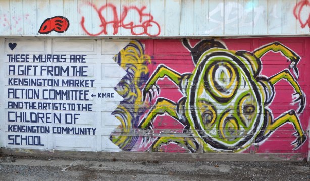 A large green and black beetle (or a similar insect) painted on a garage door along with words