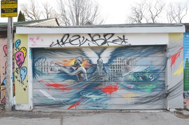 A mural on a garage door, a wispy picture of a man, an owl and a pair of eyes