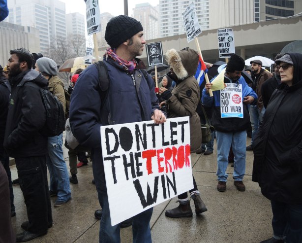 A man is holding a placard that says Don't Let the Terror Win at a protest