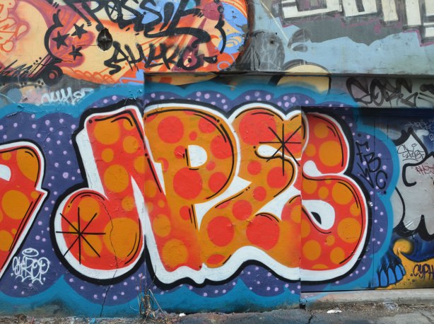 new graffiti tag art in the alley, red with yellow polka dots on blue background
