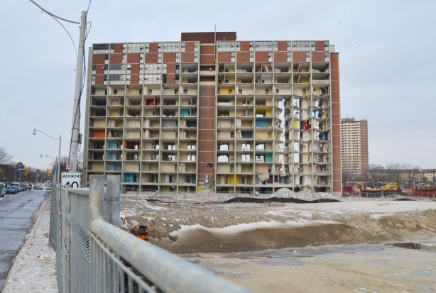A large 14 storey brick clad apartment building in the initial stages of being demolished. 