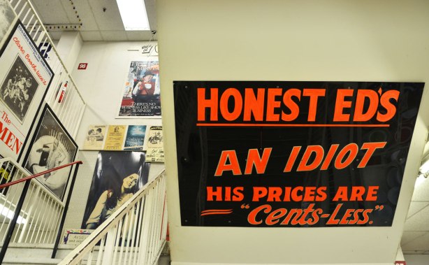 A stairwell at Honest Eds store with a large black and red sign that reads "Honest Ed's an Idiot, his prices are cents-less"