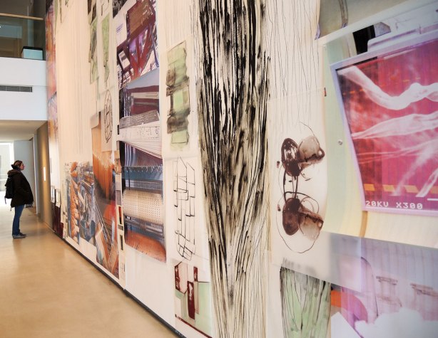 A woman is looking at a large art piece on a wall.  A collage called Obsolescence by Shelagh Keeley,