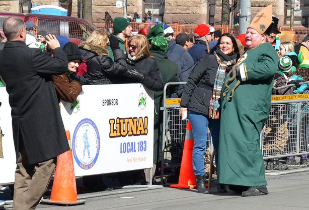 A heavyset man wearing long green robe and carrying a plastic snake. He is supposed to be St. patrick, the patron saint of Ireland who drove the snakes out of Ireland many centuries ago.