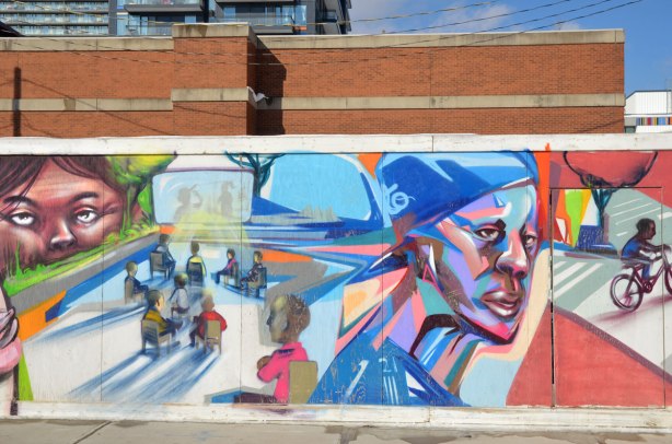 Colourful graffiti on hoardings around a construction site.Young man in blue baseball cap