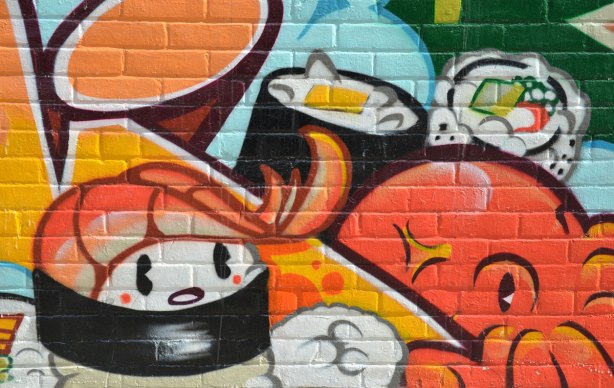 sushi street art, part of a mural on the side of a store on a corner lot that has a number of Japanese motifs. 