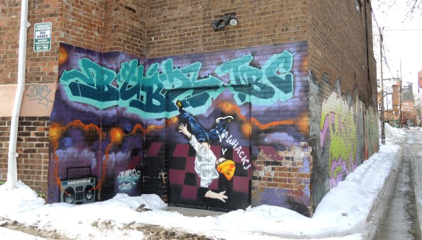 Mural over the back entrance to 509 Dance, ghetto blaster in one corner, a guy break dancing, and upside down almost, in the picture.  He's wearing a yellow hat. 