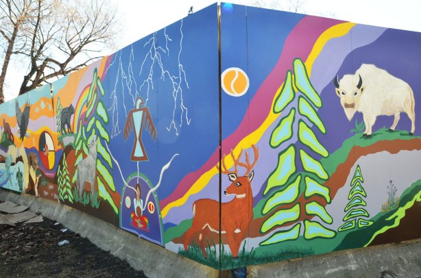 part of First Nations story/legend themed mural painted on wood construction hoardings in Allan Gardens a deer with antlers stands by a pine tree. 