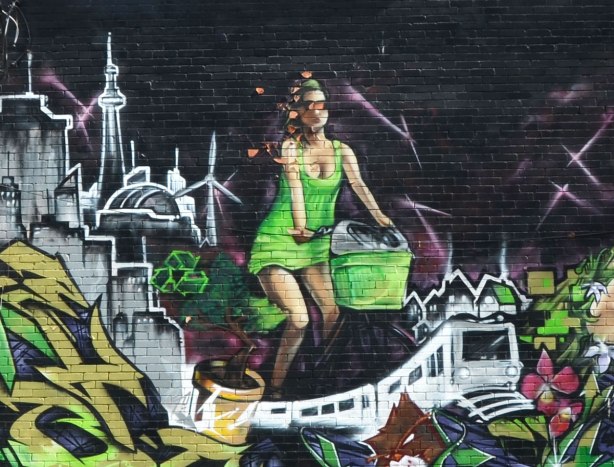 Part of a street art painting of a woman on a bike with a Toronto scene behind her including the CN Tower and a TTC subway car below her.