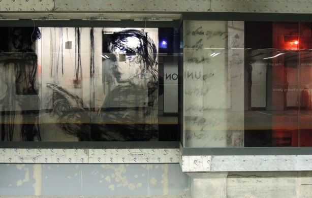 new art, pictures of people on the subway, on glass panels installed at Union Station platform, a woman's face in profile.  You can see traces of the construction behind her. 
