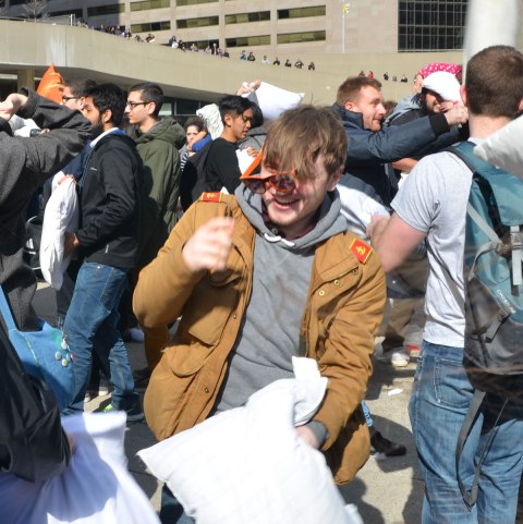 A young man's glasses are falling off because he's just been hit with a pillow. 