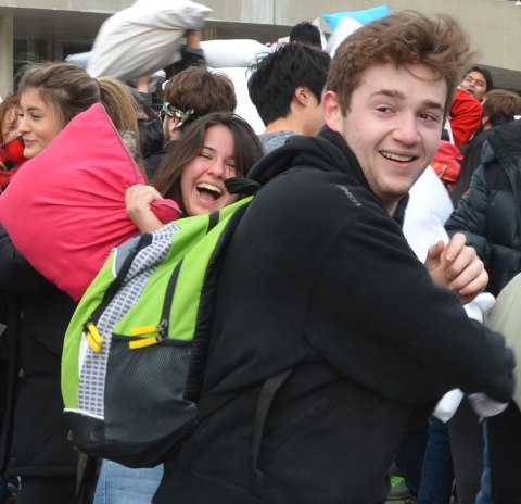 Young people having a pillow fight and laughing. 