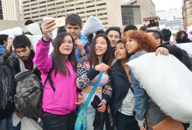 A group of young people taking a selfie photo at a pillow fight. 