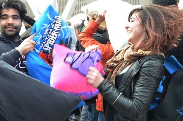 Man with a spiderman pillow and woman with a pink pillow at a pillow fight