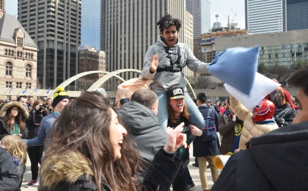 A young man on the shoulders of another at a pillow fight at Nathan Phillips Square. 