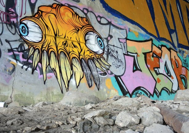 a yellow grominator street art painting, bulging veiny eyes and many crooked sharp teeth