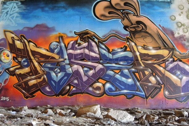 street art picture of a poser bunny with an outstretched skinny arm pointing to the left.  He's on a large intricate tag. 