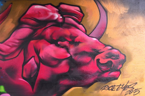 street art painting under a railway bridge - a pink, maroon and red bull