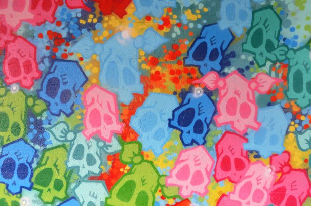 street art painting under a railway bridge - multicolored skulls