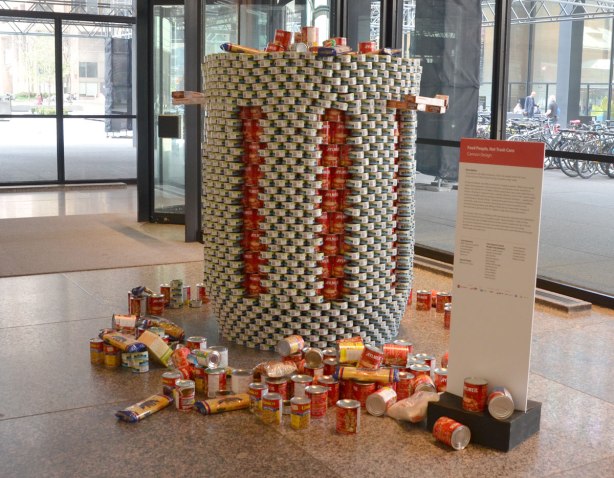 sculptures on display that were entered in a contest in support of the Daily Food Bank, sculptures made of canned food in a theme pertaining to hunger awareness - an oversized trash can overflowing with cans of food. The trash can is made of gray coloured cans