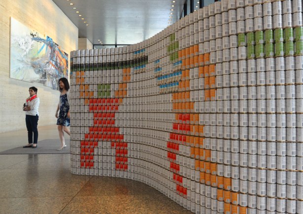 sculptures on display that were entered in a contest in support of the Daily Food Bank, sculptures made of canned food in a theme pertaining to hunger awareness - a white curved wall with two symbols representing sports on it