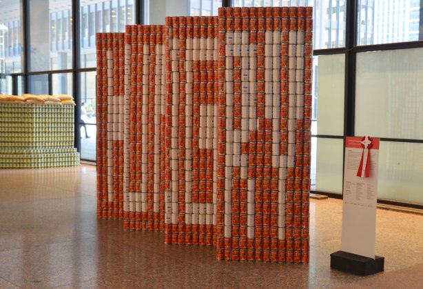 sculptures on display that were entered in a contest in support of the Daily Food Bank, sculptures made of canned food in a theme pertaining to hunger awareness - from one angle this sculpture is a red wall with the word HUNGRY written on it in block white letters