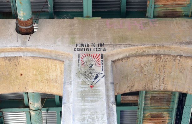 graffiti on the concrete supports under a bridge - words 'power to the creative people"