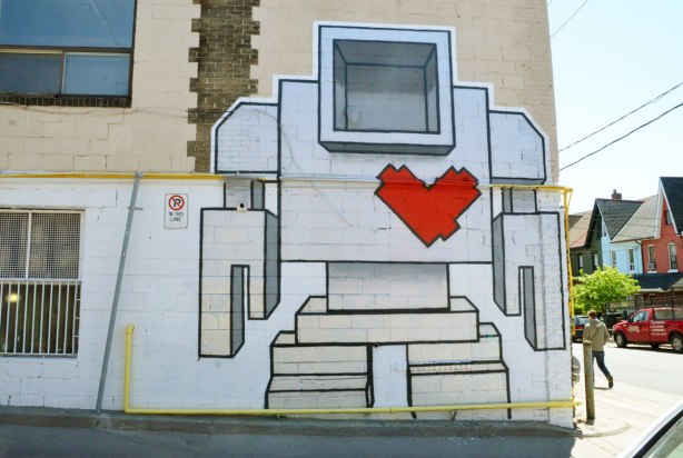 a very large lovebot painted on a wall.  He is close to two storeys tall. 