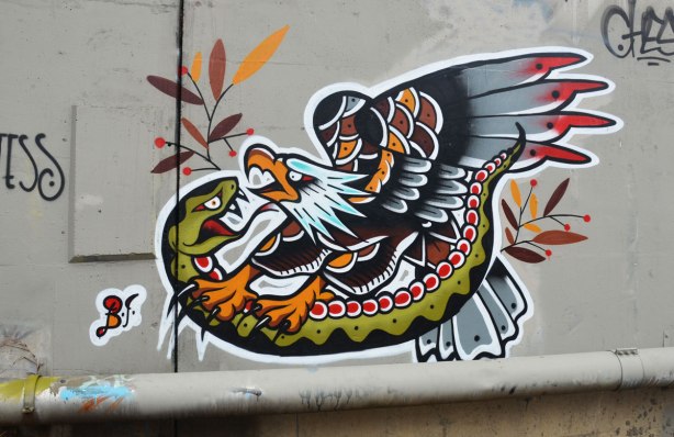 Street art painting of an eagle attacking a snake.