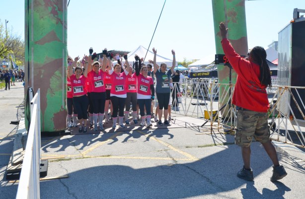 A team dressed in bright pink tops await their turn to start the race at the course start line. 